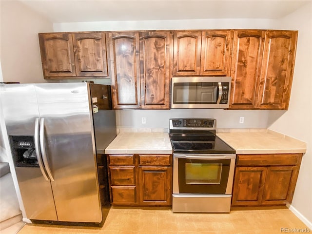 kitchen with tile counters and appliances with stainless steel finishes