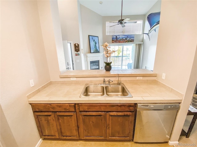 kitchen featuring tile countertops, ceiling fan, dishwasher, and sink