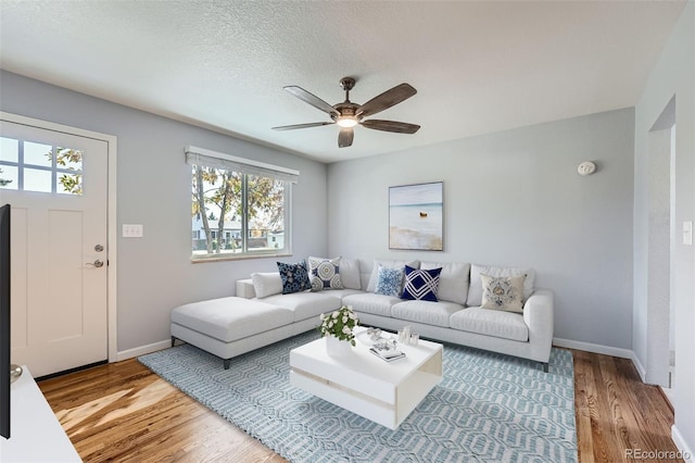 living room featuring light hardwood / wood-style flooring, a textured ceiling, plenty of natural light, and ceiling fan