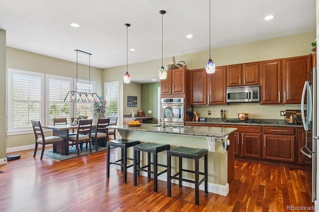 5463 Killen Ave, Castle Rock, CO 80104 - kitchen with appliances with stainless steel finishes, a kitchen breakfast bar, dark wood-style flooring, dark stone counters, and plenty of natural light