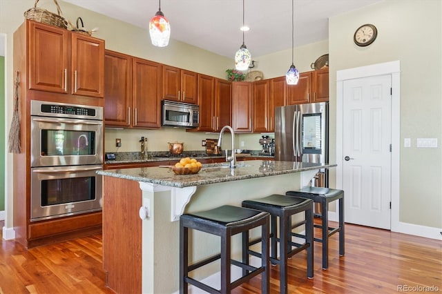 5463 Killen Ave, Castle Rock, CO 80104 - kitchen with stainless steel appliances, wood finished floors, dark stone counters, and a breakfast bar area