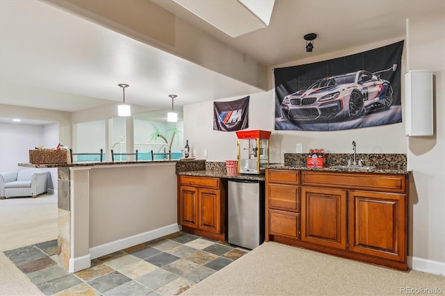 5463 Killen Ave, Castle Rock, CO 80104 - kitchen with fridge, brown cabinetry, a peninsula, dark stone countertops, and pendant lighting