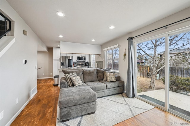 living area with wood finished floors, visible vents, and recessed lighting