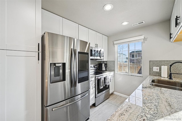 kitchen featuring appliances with stainless steel finishes, backsplash, a sink, and visible vents