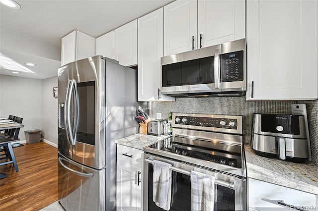 kitchen featuring stainless steel appliances, white cabinets, backsplash, and dark wood-style floors