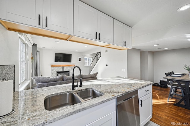 kitchen featuring a fireplace, a sink, white cabinetry, dishwasher, and dark wood finished floors