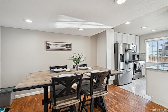 dining area featuring light wood finished floors, a textured ceiling, and recessed lighting