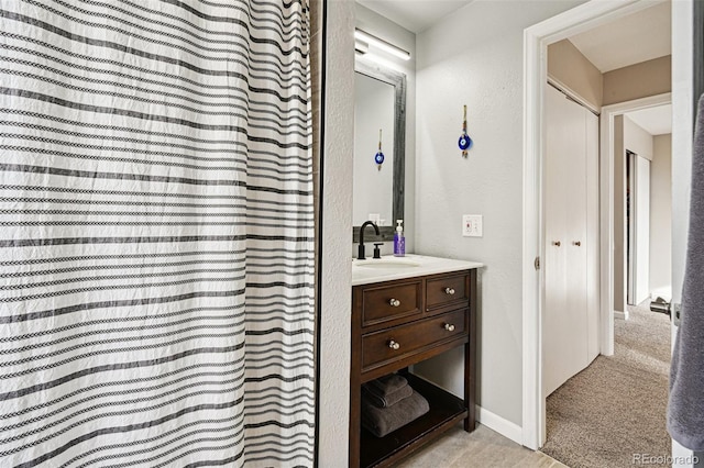 bathroom with a textured wall, a shower with curtain, baseboards, and vanity