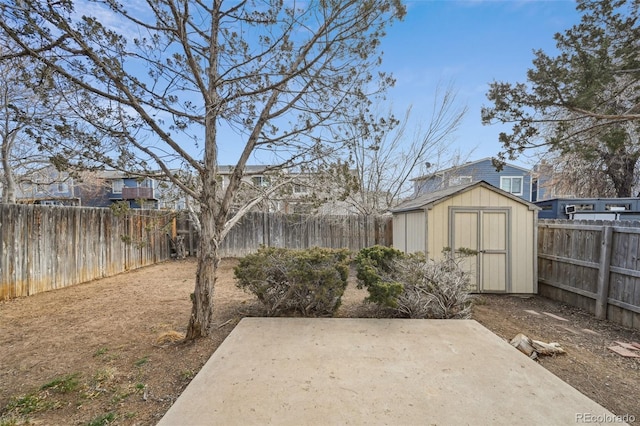 view of yard featuring a patio area, a fenced backyard, a shed, and an outbuilding