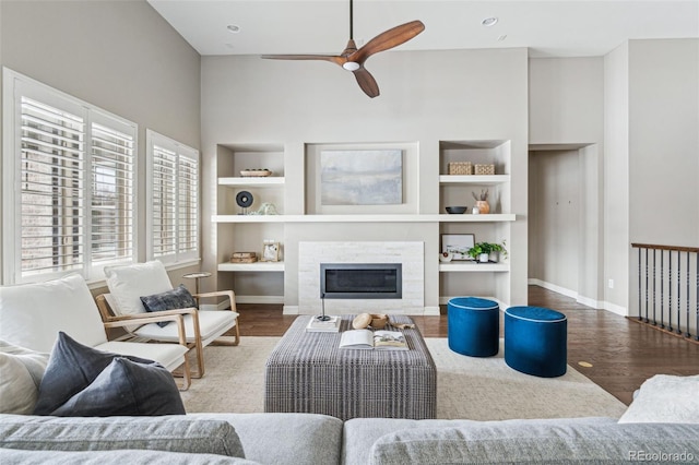 living room featuring built in shelves, ceiling fan, and hardwood / wood-style floors