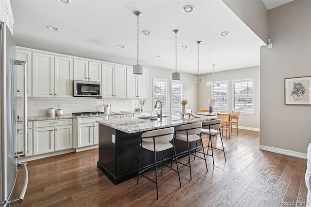 kitchen with sink, white cabinetry, appliances with stainless steel finishes, and a center island with sink