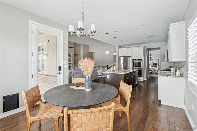 dining area with sink, dark hardwood / wood-style floors, and a chandelier