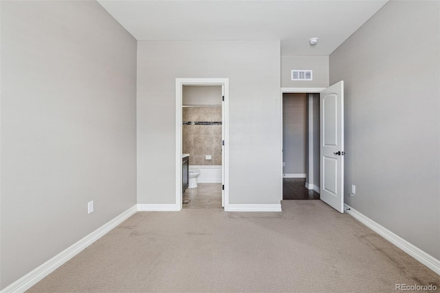 unfurnished bedroom featuring carpet flooring and ensuite bathroom