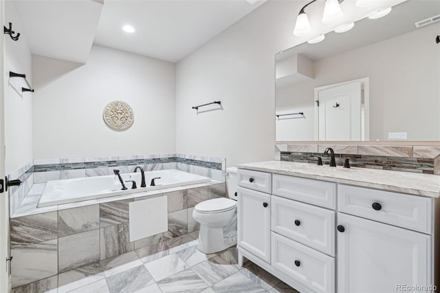 bathroom featuring tiled bath, toilet, and vanity