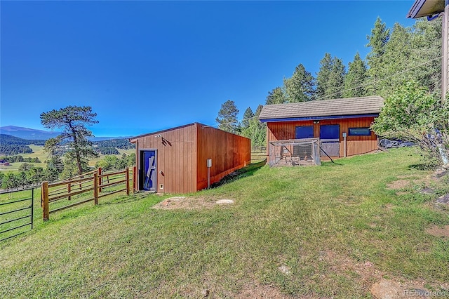 view of outbuilding featuring an outbuilding, a rural view, an exterior structure, and a mountain view