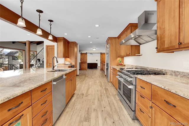 kitchen featuring decorative light fixtures, a barn door, appliances with stainless steel finishes, ventilation hood, and light stone countertops