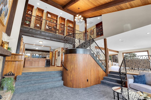 stairway with wooden ceiling, beverage cooler, a towering ceiling, beam ceiling, and an inviting chandelier