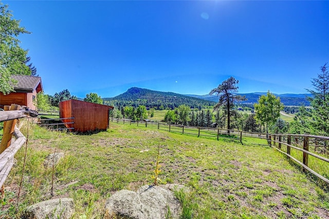 view of yard with an exterior structure, an outbuilding, a rural view, and a mountain view