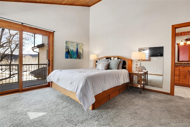 bedroom with access to exterior, light colored carpet, baseboards, and ensuite bathroom