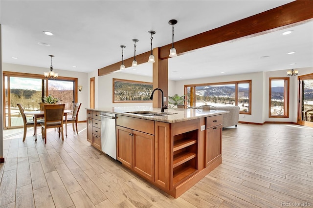 kitchen with pendant lighting, stainless steel dishwasher, a sink, and light stone countertops