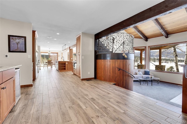 interior space featuring light wood-style floors, baseboards, and beam ceiling