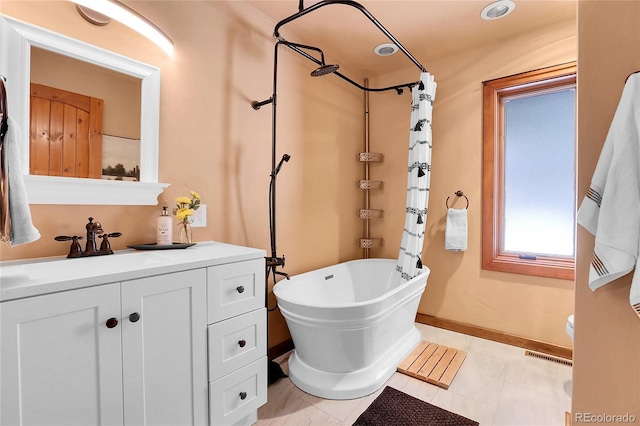 full bath featuring visible vents, vanity, a freestanding tub, baseboards, and walk in shower