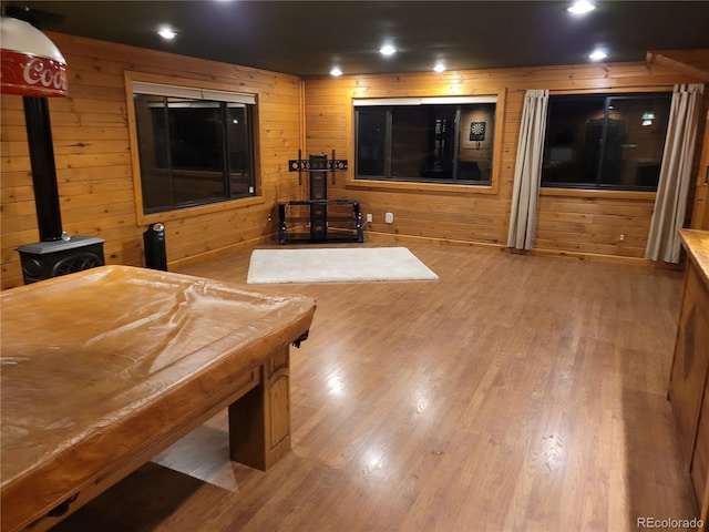 rec room with a wood stove, wooden walls, wood finished floors, and recessed lighting