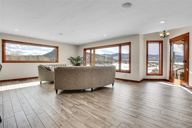 living room with light wood-style flooring, recessed lighting, a mountain view, and baseboards