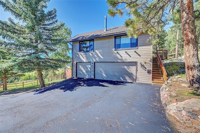 view of home's exterior featuring driveway, fence, stairway, and a garage