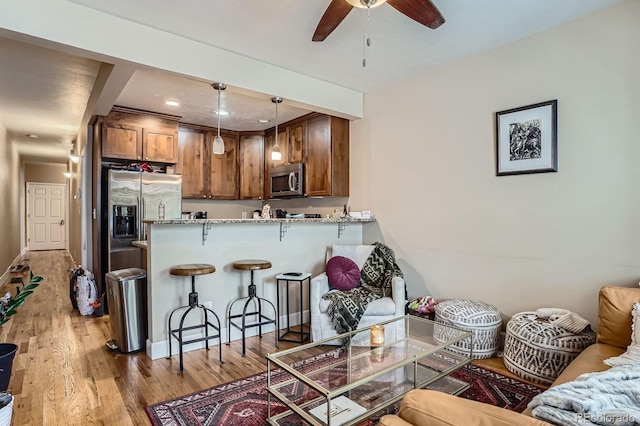 2838 Decatur St, Denver, CO 80211 - kitchen featuring stainless steel appliances, a kitchen bar, brown cabinetry, ceiling fan, and light wood-type flooring