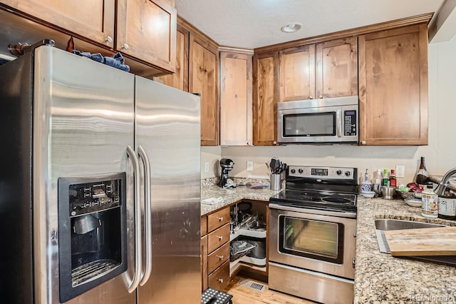 2838 Decatur St, Denver, CO 80211 - kitchen featuring appliances with stainless steel finishes, light stone countertops, a sink, and brown cabinets
