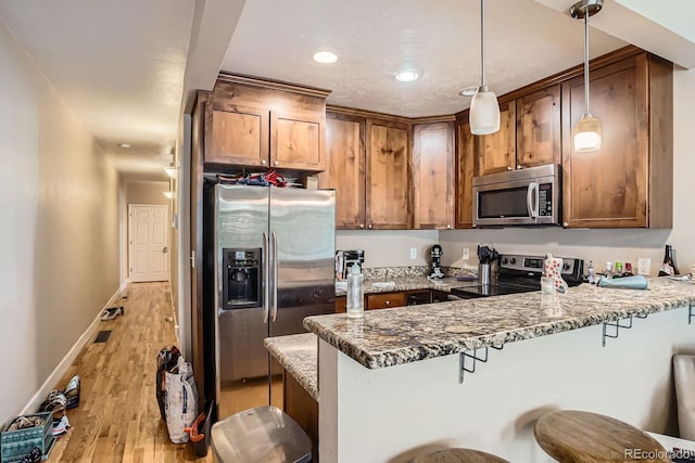 2838 Decatur St, Denver, CO 80211 - kitchen with stainless steel appliances, a peninsula, a breakfast bar, light stone counters, and light wood-style flooring