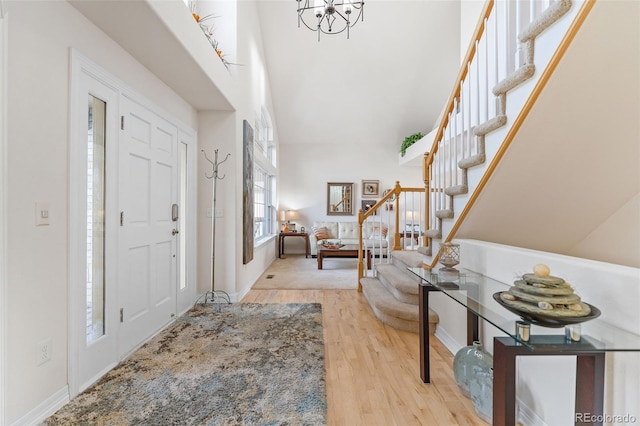 foyer with a towering ceiling, an inviting chandelier, and light wood-type flooring