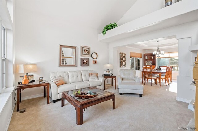 carpeted living room with a towering ceiling, a chandelier, and a tray ceiling