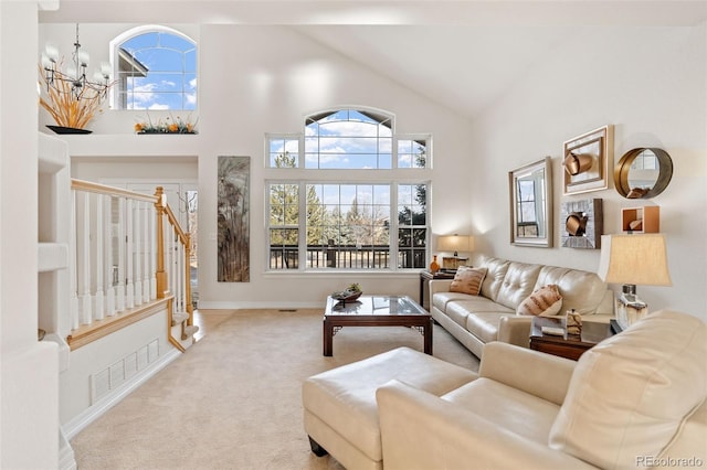 carpeted living room with a notable chandelier, high vaulted ceiling, and a healthy amount of sunlight