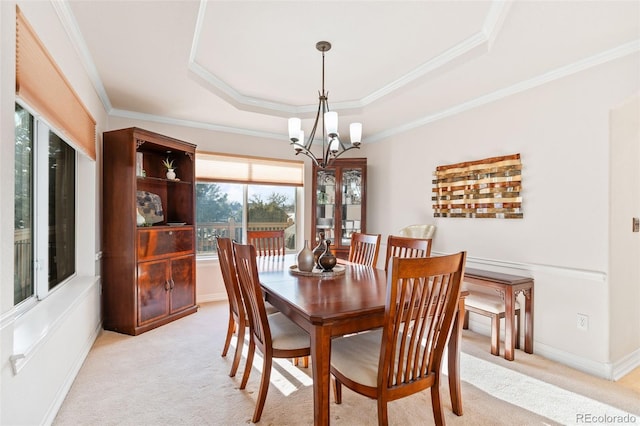 dining space featuring light colored carpet, ornamental molding, a raised ceiling, and a notable chandelier