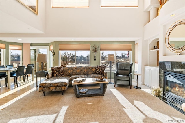 carpeted living room with built in shelves, a fireplace, and a towering ceiling