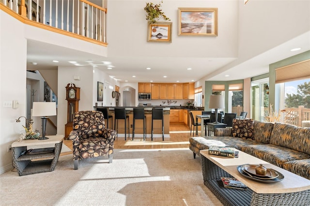 living room featuring sink, a towering ceiling, and light colored carpet