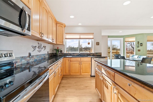 kitchen featuring dark stone countertops, sink, a wealth of natural light, and appliances with stainless steel finishes