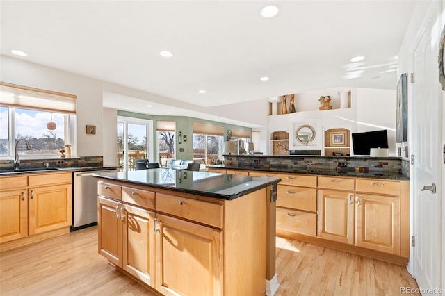 kitchen with sink, dark stone counters, a center island, and dishwasher