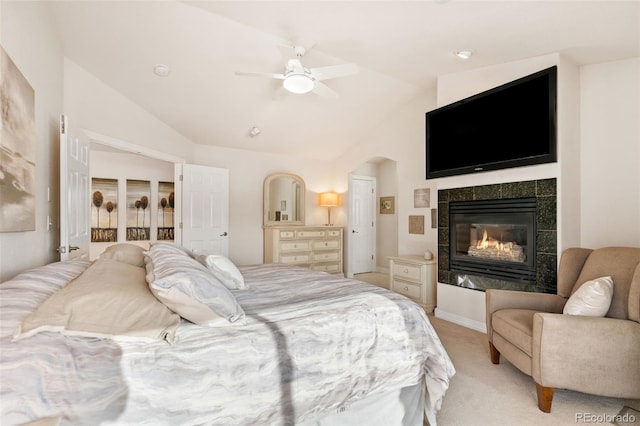 carpeted bedroom featuring ceiling fan, lofted ceiling, and a tiled fireplace