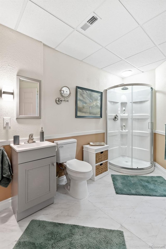 bathroom featuring vanity, a paneled ceiling, a shower with door, and toilet