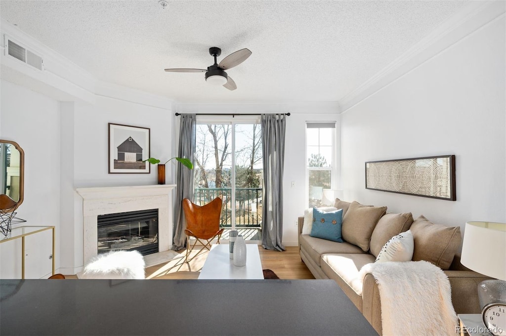 living room with ornamental molding, a textured ceiling, a fireplace, and light hardwood / wood-style flooring