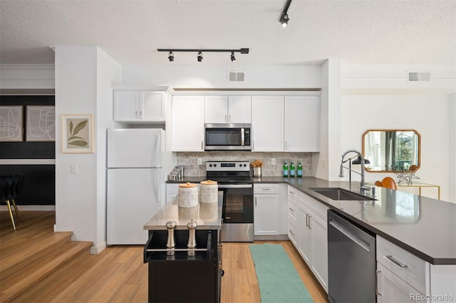 kitchen featuring stainless steel appliances, sink, white cabinets, and light hardwood / wood-style flooring