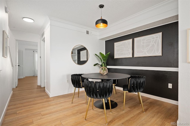 dining area with crown molding, light hardwood / wood-style flooring, and a textured ceiling