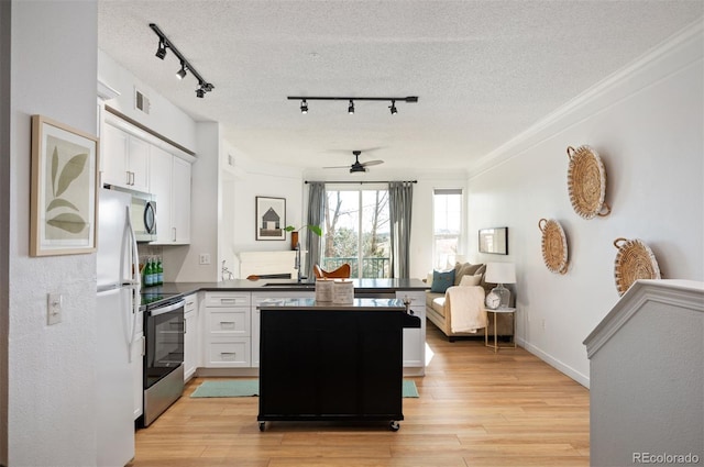 kitchen featuring white cabinetry, appliances with stainless steel finishes, a textured ceiling, and light wood-type flooring