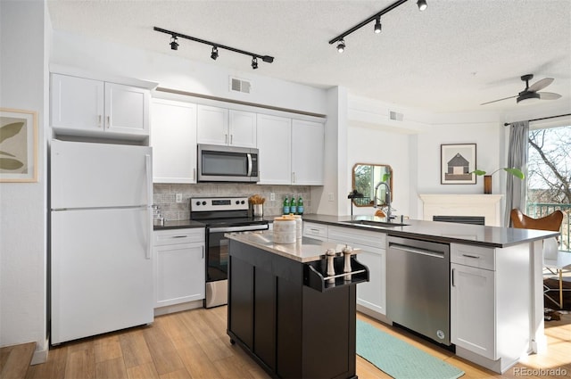 kitchen with appliances with stainless steel finishes, a center island, sink, and white cabinets