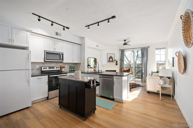 kitchen with light hardwood / wood-style flooring, white cabinetry, stainless steel appliances, a kitchen island, and kitchen peninsula