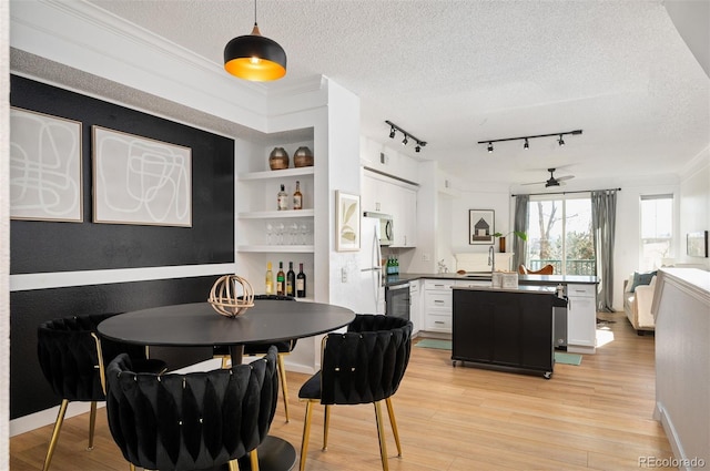 dining area with built in features, light hardwood / wood-style flooring, and a textured ceiling