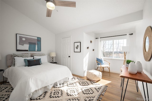 bedroom featuring ceiling fan, lofted ceiling, a closet, and light wood-type flooring